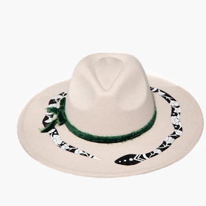May include: A white felt fedora hat with a green velvet band and a black and white snake design on the brim.
