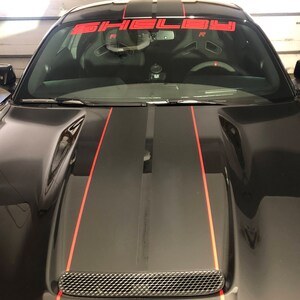 May include: Black car with red racing stripes and a Shelby windscreen banner.