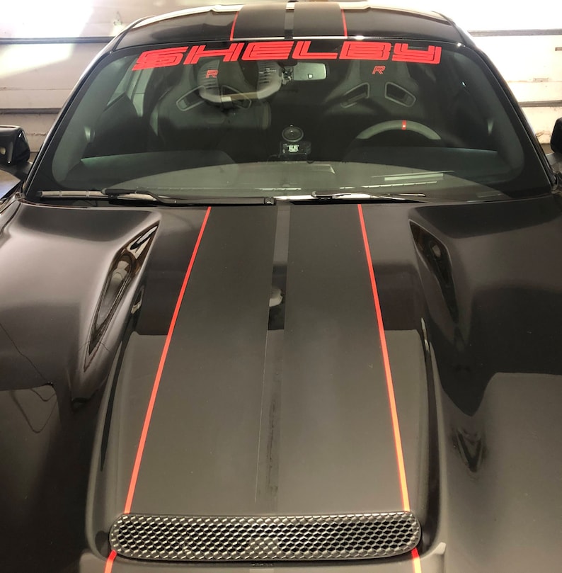 May include: Black car with red racing stripes and a Shelby windscreen banner.