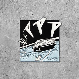 Puede incluir: Pin cuadrado de esmalte con fondo negro y texto blanco "ATP". Un coche blanco se representa en una carretera azul claro, con líneas y detalles blancos. El pin tiene un acabado brillante.