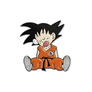An enamel pin design of the character kid Goku from the classic anime, Dragon Ball. Goku appears to be sleeping.