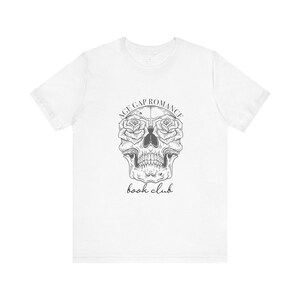May include: White t-shirt with a black and white skull graphic. Roses replace the eye sockets. The text "AGE GAP ROMANCE" curves above the skull, with "book club" written below in a script font.