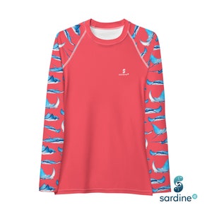May include: A coral-colored long-sleeve rash guard with a white crew neck and blue manta ray pattern on the sleeves. The shirt has the brand name "sardine" printed on the chest.
