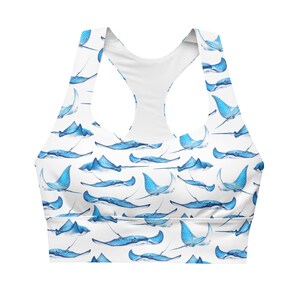 May include: White sports bra featuring a pattern of blue stingrays. The bra has a racerback design and is made of a soft, comfortable material. The stingrays are in various poses, creating a dynamic and eye-catching design.