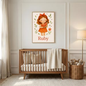 Pode incluir: Uma impress&atilde;o emoldurada com uma ilustra&ccedil;&atilde;o em aquarela de uma menina segurando uma fatia de melancia. A menina tem cabelo ruivo e usa um vestido laranja. A impress&atilde;o &eacute; rotulada como "Ruby" em texto vermelho.