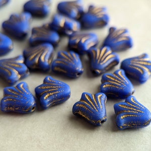 May include: A group of blue glass beads with gold accents. The beads are shaped like a flower with a ruffled edge.
