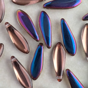 May include: An assortment of iridescent teardrop-shaped beads in shades of bronze, purple, and blue. The beads have a metallic sheen and a small, silver-colored cap at one end. These beads are ideal for jewelry making and crafting.