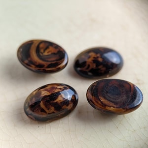 May include: Four oval-shaped buttons with a brown and black marbled pattern.