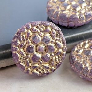 May include: Close-up of three round, purple beads with a textured, honeycomb-like pattern. The raised areas of the design are accented with gold. These decorative beads are ideal for jewelry making and craft projects.