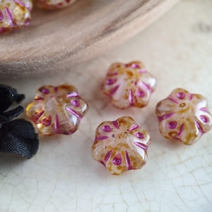 May include: Five translucent glass flower-shaped beads with a pink and brown swirl pattern.