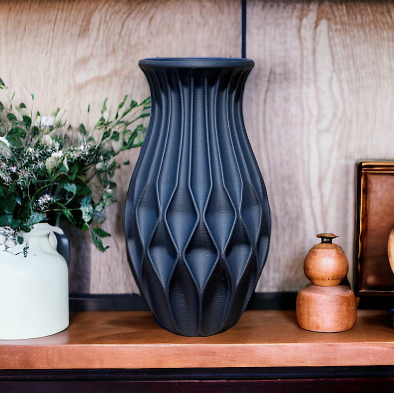 May include: A black ceramic vase with a geometric pattern. The vase is sitting on a wooden shelf.