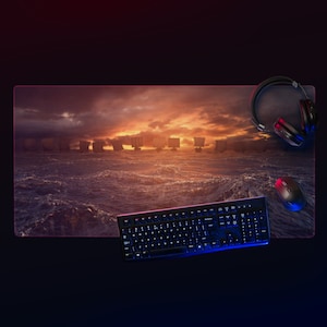 Pode incluir: Um teclado e um rato pretos com um auscultador preto num tapete de secretária com uma cena de pôr do sol de navios a navegar no oceano.