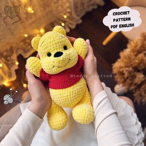 Op de afbeelding: Haakpatroon voor een geel en rood Winnie de Poeh amigurumi speelgoed. Het patroon is beschikbaar in PDF-formaat en is geschreven in het Engels. Het patroon is te koop en is beschikbaar op Etsy.