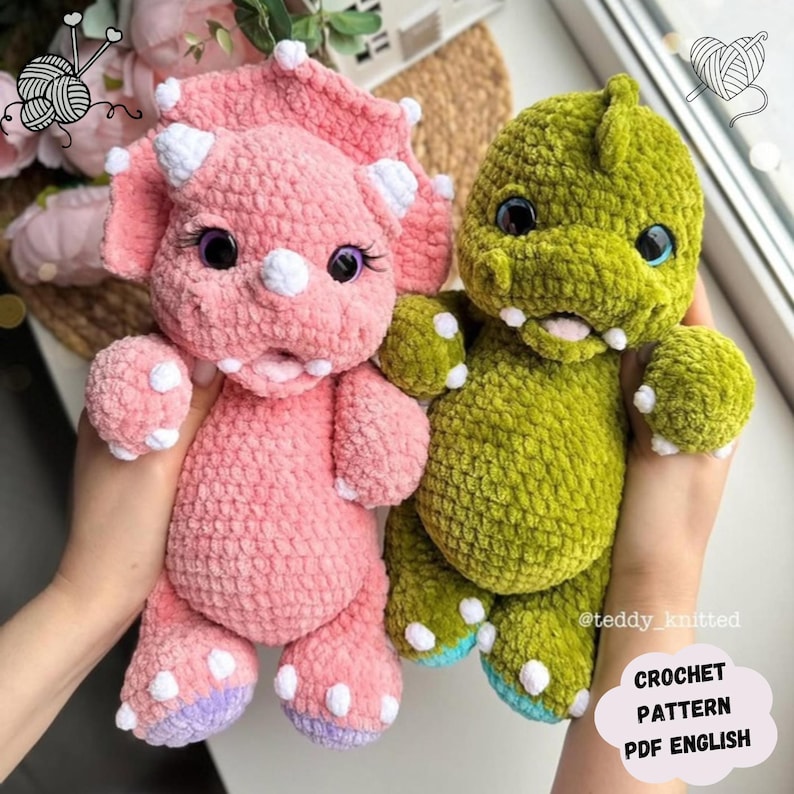 May include: Two crocheted dinosaur plushies, one pink and one green, with white accents. The pink dinosaur has purple accents on its feet. The plushies are held in a person's hands. The text "CROCHET PATTERN PDF ENGLISH" is visible in the image.