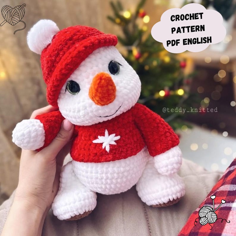 May include: Crochet pattern PDF in English for a white snowman wearing a red hat and sweater with a white snowflake. The snowman has a carrot nose and black eyes.