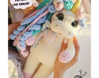 May include: Crochet pattern for a white unicorn amigurumi with a pink and blue mane, pink hooves, and a yellow horn. The pattern is available in PDF format and is written in English.