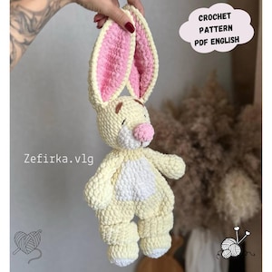 May include: A crocheted bunny toy in pale yellow with pink inner ears and a pink nose. The bunny has a white belly and brown details. The image includes the text "CROCHET PATTERN PDF ENGLISH" and "Zefirka.vlg".