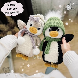 May include: Two handmade crochet penguin dolls. One penguin is wearing a green hat and scarf, the other a light purple scarf and bow. The penguins have yellow beaks and feet. The text "CROCHET PATTERN PDF ENGLISH" is in a cloud-shaped text box.