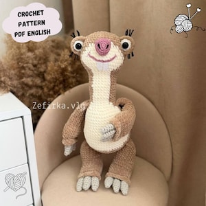 Könnte beinhalten: Ein gehäkeltes Faultier-Spielzeug in Braun-, Creme- und Rosatönen mit schwarzen Akzenten. Das Faultier hat große Augen, einen lächelnden Mund und einen langen Hals. Der Text auf dem Bild lautet "CROCHET PATTERN PDF ENGLISH" und "Zefirka.vlg".