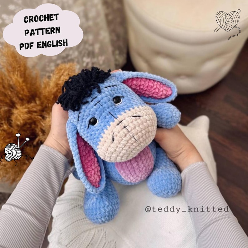 May include: A crocheted blue Eeyore plush toy with pink ears and a black mane. The toy is being held by a person's hands. The text "@teddy_knitted" is visible in the bottom right corner of the image.