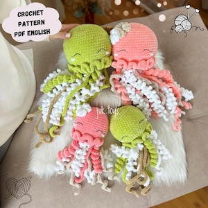Puede incluir: Cuatro medusas de ganchillo hechas a mano en tonos verdes y rosas, con detalles blancos y beige. Las medusas tienen caras sonrientes y tentáculos fluidos. La imagen incluye el texto "CROCHET PATTERN PDF ENGLISH".