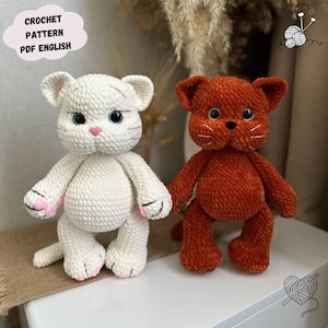 Puede incluir: Dos peluches de gato de ganchillo. Uno es blanco con detalles en rosa, el otro naranja. Ambos tienen detalles, incluyendo bigotes y ojos de botón. El texto "CROCHET PATTERN PDF ENGLISH" está en una nube.