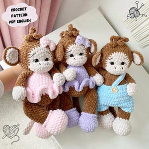 Può includere: Tre bambole a forma di scimmia all'uncinetto fatte a mano, marroni, bianche e dai colori pastello. Una scimmia indossa un vestito rosa, un'altra un vestito viola e la terza una tuta blu. Il testo "CROCHET PATTERN PDF ENGLISH" è in una nuvola.