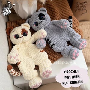 May include: Two handmade crochet cat plushies. One is cream-colored with brown spots, the other is gray. Both have large eyes and pink paw pads. The image includes text that says "CROCHET PATTERN PDF ENGLISH".