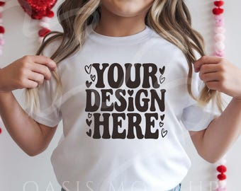 Puede incluir: Camiseta blanca con el texto "YOUR DESIGN HERE" en letras negras con pequeños corazones alrededor del texto.