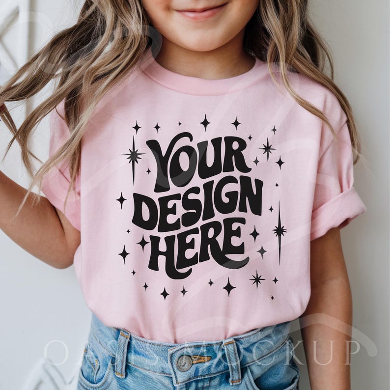 May include: A pink t-shirt with a black graphic that says "Your Design Here" surrounded by small stars.