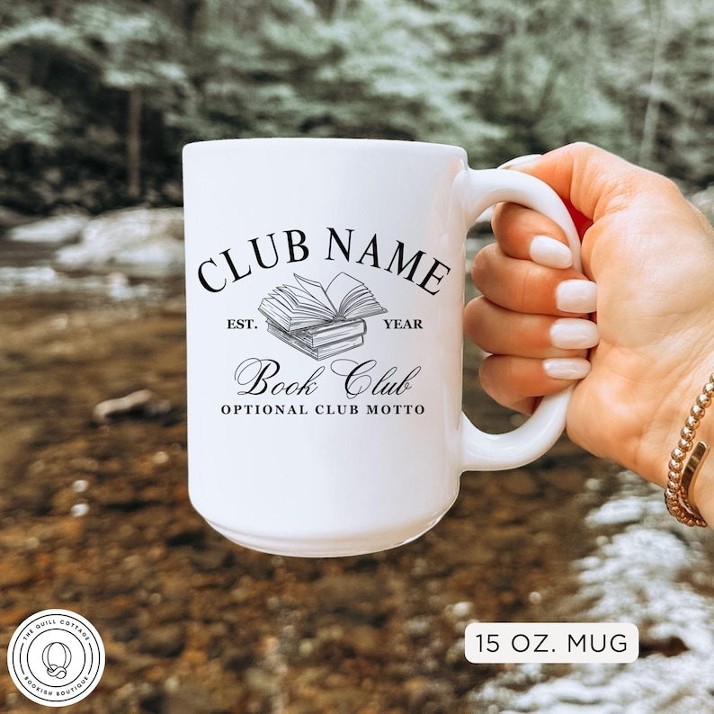 May include: White ceramic mug with the text "CLUB NAME" above a stack of books and the words "Book Club". The mug also has the text "EST. YEAR" and "OPTIONAL CLUB MOTTO". The mug is 15 oz.