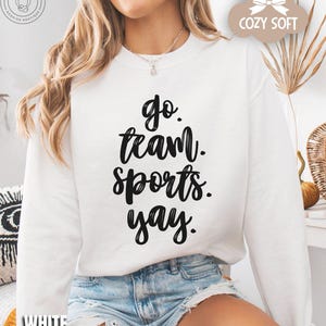 May include: White sweatshirt with black text that reads 'go team sports yay.'