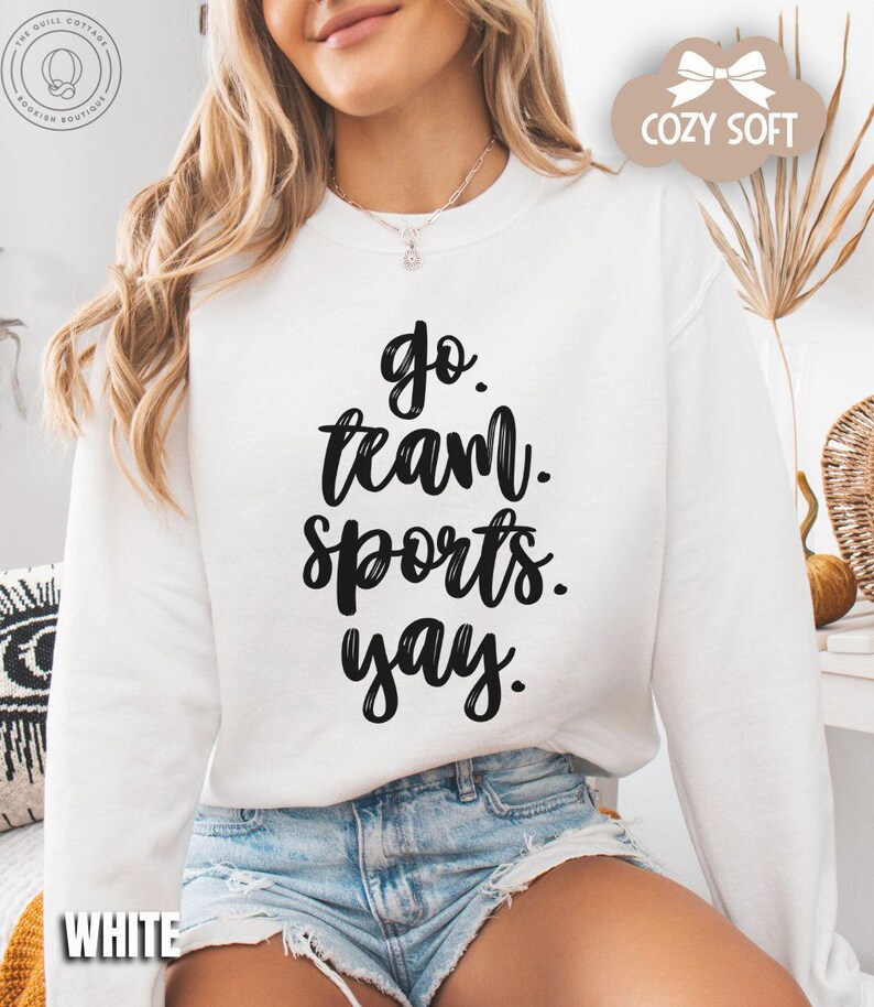 May include: White sweatshirt with black text that reads 'go team sports yay.'