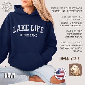 May include: A navy blue hooded sweatshirt featuring the white text LAKE LIFE and CUSTOM NAME printed on the chest. The hoodie includes a front kangaroo pocket and long sleeves. Text on the right side details product features and production.