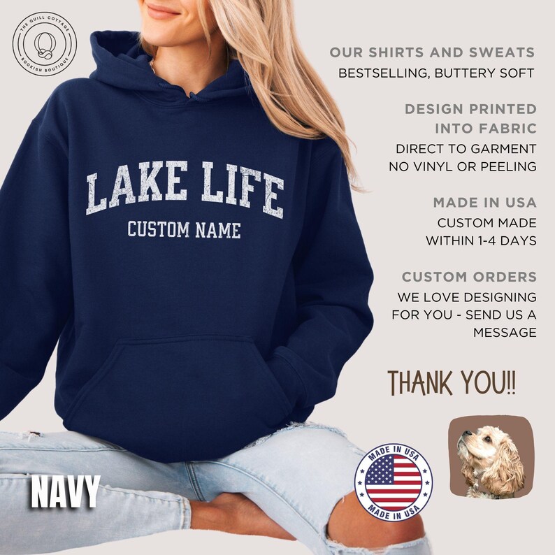 May include: A navy blue hooded sweatshirt featuring the white text LAKE LIFE and CUSTOM NAME printed on the chest. The hoodie includes a front kangaroo pocket and long sleeves. Text on the right side details product features and production.