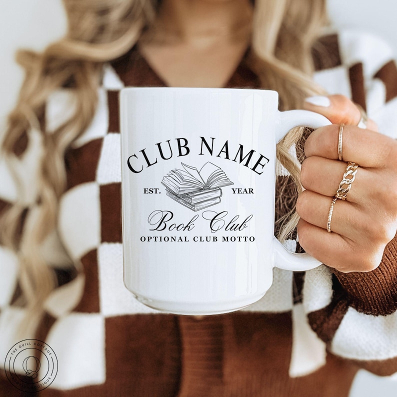 May include: White ceramic mug with a black and gray book club design. The mug features the words "Club Name," "Book Club," and "Optional Club Motto." The design includes an illustration of stacked books. The mug has a large handle.