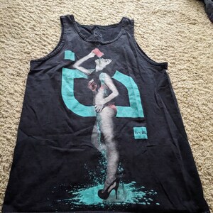 May include: Black tank top with a graphic print of a woman in a swimsuit pouring water from a cup. The graphic is in shades of blue and pink. The text "tmLs" is printed on the bottom right corner of the shirt.