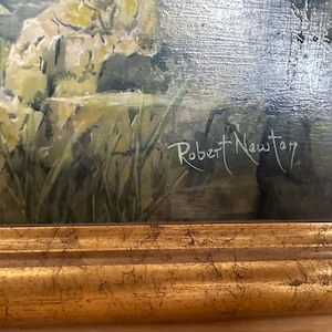May include: An oil painting depicting a landscape scene with a body of water, rocks, and greenery. The artwork is signed "Robert Newton" in white script. The painting is framed in a gold-colored, ornate frame, adding a touch of elegance.