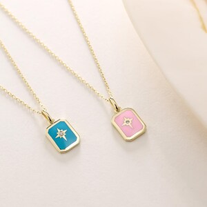 May include: Two gold necklaces with rectangular pendants. One pendant is turquoise blue with a white star, the other is pink with a white star.