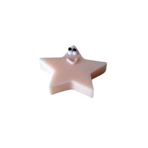 May include: A light pink star-shaped soap with a smiling face and black eyes.