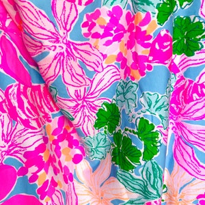 以下が含まれることがあります： ピンクとグリーンの花柄のブルーとホワイトの生地。生地はトロピカルな雰囲気で、夏にぴったりです。