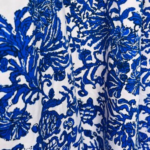 Peut inclure: Tissu blanc avec un motif floral bleu. Le motif présente des motifs complexes de fleurs, de feuilles et de vignes.