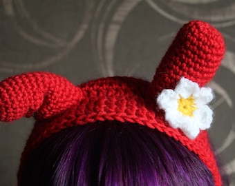 May include: A red crocheted headband with two large horns and a white crocheted flower with a yellow center.