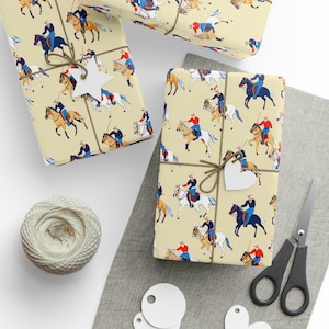 May include: A yellow gift wrap with a repeating pattern of riders on horses playing polo. The riders are wearing red, white, and blue uniforms. The horses are brown and white. The background is a light yellow.