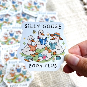 May include: A sticker featuring a cartoon illustration of four geese reading books, with the text "SILLY GOOSE BOOK CLUB". The geese are depicted with glasses, hats, and flowers. The sticker is white with a light blue border.
