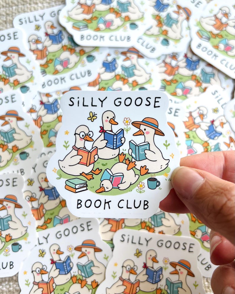 May include: A collection of stickers featuring a cartoon illustration of geese reading books. The stickers have the text "SILLY GOOSE BOOK CLUB". The geese are depicted with hats, glasses, and books in various colors. A hand holds one sticker.