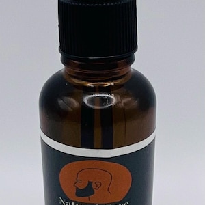 May include: A brown glass bottle with a black dropper top and a white label. The label has a brown circle with a cartoon illustration of a person with a beard. The text on the label reads "Natural Care Peppermint Beard Oil".
