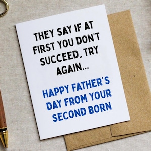 May include: A white Father's Day card with the text "THEY SAY IF AT FIRST YOU DON'T SUCCEED, TRY AGAIN... HAPPY FATHER'S DAY FROM YOUR SECOND BORN" in black and blue. The card is on a brown envelope.