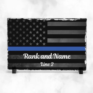 May include: Black and white American flag with a blue line across the middle. The words "Rank and Name" and "Line 2" are written below the flag.