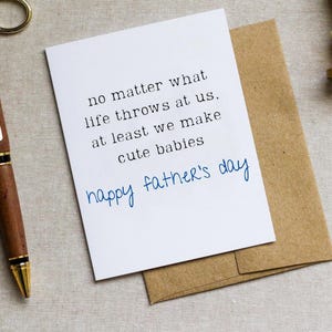May include: A white card with a handwritten message that reads "no matter what life throws at us. at least we make cute babies happy father's day".